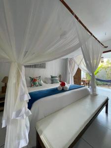 1 dormitorio con 1 cama blanca con dosel en Pousada Suites Nativas, en Trancoso