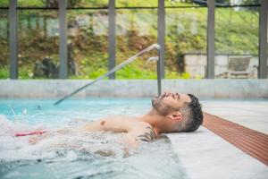 un hombre tendido en una piscina en Gran Hotel Las Caldas by blau hotels en Las Caldas