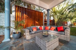 ein Sofa auf einer Terrasse mit roten Kissen in der Unterkunft Villa Lyah in La Saline-Les-Bains