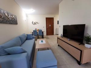 a living room with a blue couch and a tv at Villa Callisto in Loutra