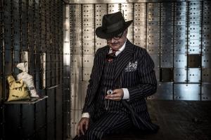 a man in a suit and hat is looking at his cell phone at Hotel Gotham in Manchester