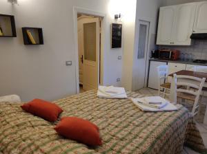 a bedroom with a bed with red pillows and a kitchen at La piccola Posta di Cortona in Cortona