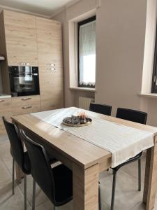 una mesa de madera en una cocina con sillas negras en Sweet Home en Savigliano