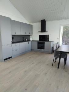 eine Küche mit weißen Schränken und einem Tisch mit Stühlen in der Unterkunft Torghatten bnb in Brønnøysund