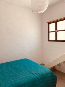 Un dormitorio con una cama azul y una ventana en Casita cerca de T1 y T2 del aeropuerto y Foro Sol, en Ciudad de México