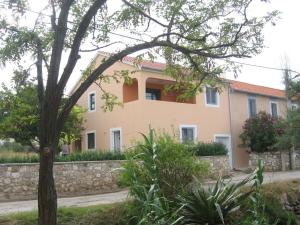 a house with a stone wall and a tree at Nevera Apartments Pašman,Banj in Banj