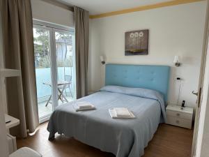 1 dormitorio con cama azul y balcón en Hotel Irene, en Lignano Sabbiadoro