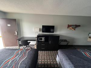 Habitación de hotel con cama y escritorio con TV. en Executive Inn, en Pelham