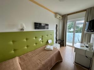 a bedroom with a bed with a green headboard at Hotel Irene in Lignano Sabbiadoro