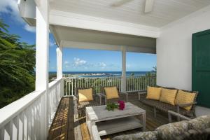 un porche con sillas, una mesa y el océano en Buccaneer Hill Main House home, en Governorʼs Harbour