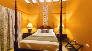 a bedroom with a four poster bed and yellow walls at La Quinta en Alamos in Álamos