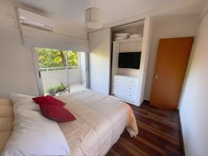 1 dormitorio con 1 cama blanca grande con almohadas rojas en Departamento Moderno La Plata, Plaza España en La Plata