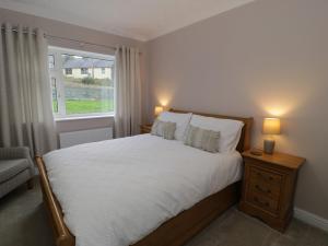 a bedroom with a large bed and a window at Cynefin in Llandyfrydog