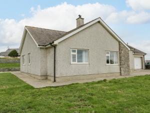 a house with a green lawn in front of it at Cynefin in Llandyfrydog