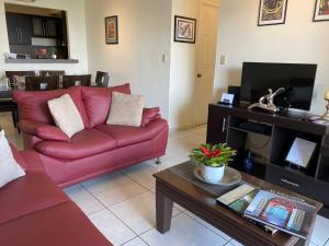 Sala de estar con sofá rojo y mesa de centro en Luxury Modrn Apartment, w/amazing view, 3BR,Escalon,Exclus,Secur, en San Salvador