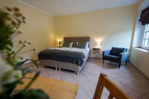 a bedroom with a bed and a blue chair at Hotel Obermühle in Görlitz