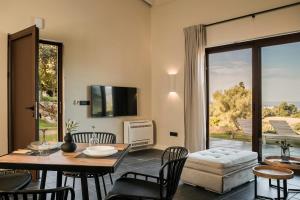 een woonkamer met een tafel en stoelen en een televisie bij FRG Villas - Villa Cantare in Kefallonia