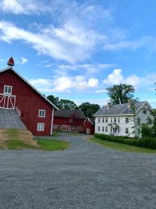 a red barn and white buildings on a road at Storsand Gård in Trondheim