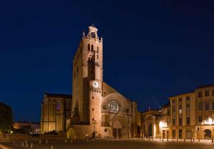 un gran edificio con una torre de reloj por la noche en Appartement de prestige – rue des Arts en Toulouse