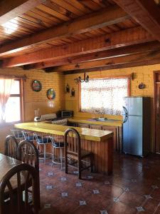 cocina con nevera, mesa y sillas en Cabañas Lupita, en Mazamitla
