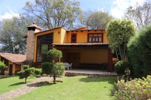 una casa amarilla con porche y patio en Cabañas Lupita, en Mazamitla