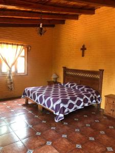 1 cama grande en una habitación con una cruz en la pared en Cabañas Lupita, en Mazamitla