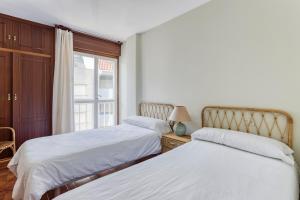 a bedroom with two beds and a window at Apartamentos Granxola in Sanxenxo