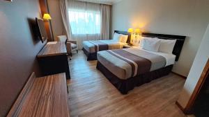 um quarto de hotel com duas camas e uma televisão em Hotel Diego de Almagro Chillan em Chillán