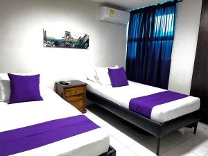 dwa łóżka w pokoju fioletowo-białym w obiekcie Hotel Boston Superior w mieście Barranquilla