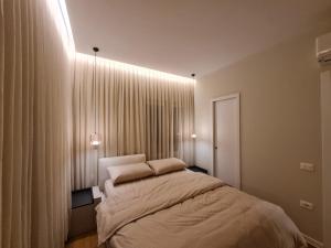 Schlafzimmer mit einem Bett und einem Fenster mit Vorhängen in der Unterkunft Adore - Modern Apartment in Tirana