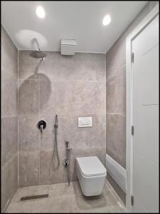ein Bad mit einer Dusche und einem WC in der Unterkunft Adore - Modern Apartment in Tirana