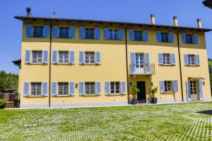 a yellow house with blue windows and a yard at Vigna Dell'Acqua in Santo Stefano Belbo
