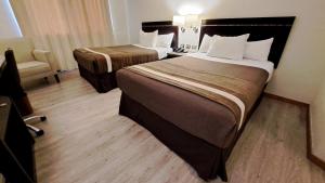 um quarto de hotel com duas camas e uma cadeira em Hotel Diego de Almagro Curicó em Curicó