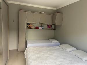 um pequeno quarto com duas camas e armários em Loft central Sant Helena Gramado Rs em Gramado
