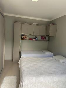 duas camas num pequeno quarto com lençóis brancos em Loft central Sant Helena Gramado Rs em Gramado