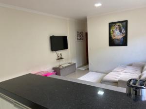 uma sala de estar com um sofá e uma televisão de ecrã plano em Loft central Sant Helena Gramado Rs em Gramado