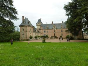 an old castle with people walking in the grass at Chateau de Bresse sur Grosne in Bresse-sur-Grosne