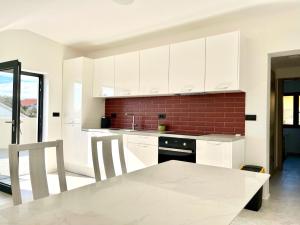 席烏倪的住宿－Apartmani Lemona，厨房配有白色橱柜、桌子和砖墙