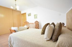 ein Schlafzimmer mit einem Bett mit Kissen und einem Kinderbett in der Unterkunft Casa Rural Manuela in As Mirans