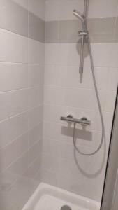 La salle de bains est pourvue d'une douche blanche avec un tuyau. dans l'établissement Appartement 2 pièces proche cathédrale, à Nantes