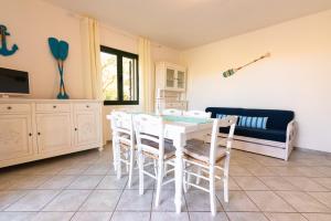 une salle à manger avec une table et des chaises blanches dans l'établissement Residence SardegnaSummer Li Cuppulati, à San Teodoro