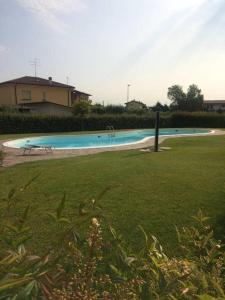 a swimming pool in a yard with a grass field at CASA VACANZE DA RIKI in Peschiera del Garda