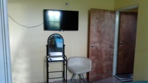 a room with a chair and a television on a wall at City View Accomodations Apt 2 in Roseau