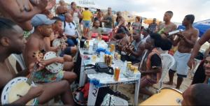 um grupo de pessoas sentadas em mesas na praia em Terraço Ribeira Casa p Temporada em Salvador