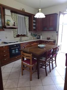 cocina con mesa de madera y sillas en Alkantara Holiday, en Francavilla di Sicilia