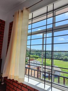 une grande fenêtre avec vue sur un bâtiment dans l'établissement SERENITY GREENS, à Madikeri