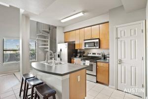 uma cozinha com um lavatório e um fogão forno superior em Balcony Skyline View Spiral Staircase Near UT em Austin