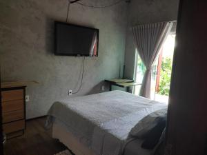 a bedroom with a bed and a television on the wall at Hostel Casa do Sossego in Brasília