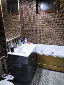 a bathroom with a white sink and a bath tub at Apartament Luxury in Constanţa