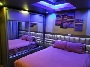 Zimmer mit 2 Betten mit Spiegeln und violetten Lichtern in der Unterkunft Apartament Luxury in Constanţa